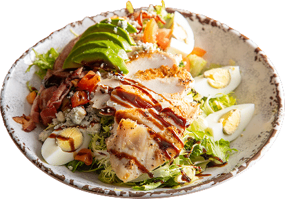 A vibrant salad bowl featuring sliced grilled chicken, avocado, chopped greens, hard‑boiled egg wedges, diced vegetables, crumbled cheese, and a drizzle of dark dressing.
